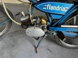 a blue motorcycle parked in a garage with a hose attached to it