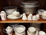 many plates and cups on a shelf in a cabinet