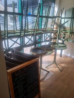 des tables et des chaises dans un restaurant, avec un tableau noir devant elles