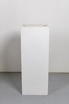 une boîte blanche percée d'un trou, posée par terre
