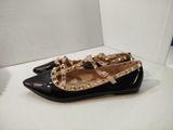 pair of black flats with gold studs on them on a white surface