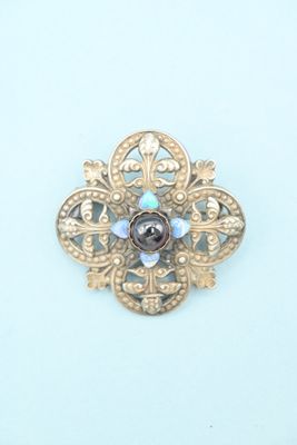 a gold brooch with a purple stone in the center