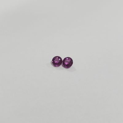 a pair of purple sapphires sitting on top of a white surface