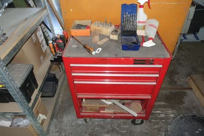 une armoire à outils rouge, sur laquelle sont posés des outils, dans un garage