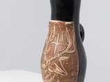 a black and brown vase sitting on a white shelf