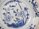 a blue and white plate with flowers and leaves on it