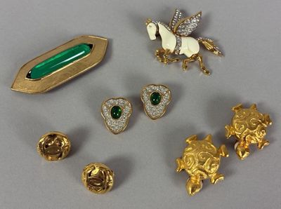 a lot of gold and green brooches on a table