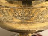 a large silver bowl with a handle on a table