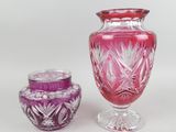 des vases en verre violet et rose posés côte à côte sur une surface blanche