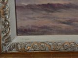 an oil painting of a landscape in a gold frame on a wooden floor