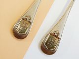 pair of silver spoons on a yellow and white surface next to each other