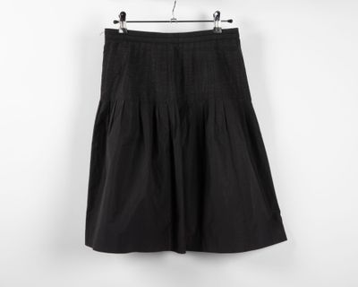 a black skirt hanging on a hanger against a white wall