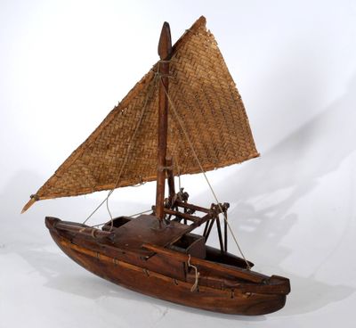 un petit bateau en bois muni d'une voile en paille