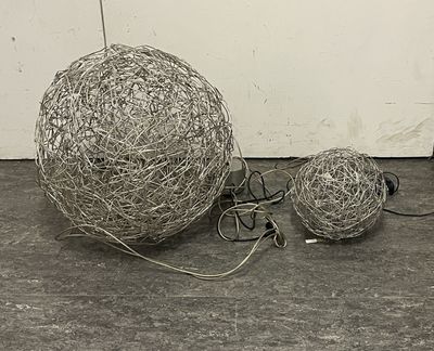 two balls of wire sitting on the floor next to each other