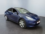 the blue tesla model y is parked in a large room