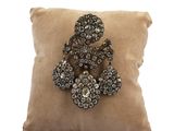 brown pillow with a brooch on top of it on a white background