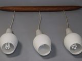 three white lights hanging from a wooden pole on a gray wall