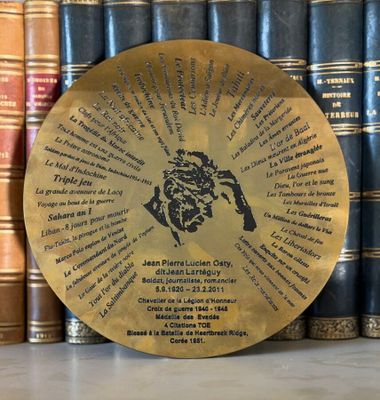 a close up of a plaque on a shelf in front of a row of books