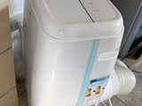 un climatiseur blanc posé par terre à côté d'un réfrigérateur
