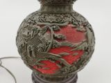 a red vase with a bird on it on a table