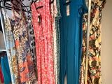 a lot of dresses hanging on a rack in a room