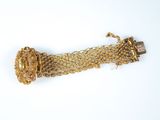 gros plan d'un bracelet en or sur une surface blanche