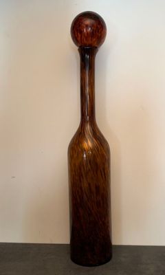 a brown glass bottle with a wooden handle on a table