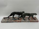 a statue of two dogs running on a marble base