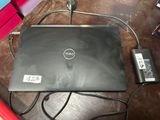 a dell laptop sitting on a table with a charger on it