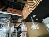 three glass lamps hanging from the ceiling in a restaurant