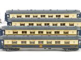 six blue and gold train cars are lined up on a white surface