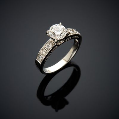 a diamond and white gold ring on a black surface