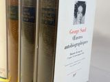 three books on a white table with a yellow ribbon in front of them