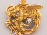 an image of a gold brooch with a bird and flowers