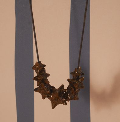 un collier accroché à un mur, avec en arrière-plan un mur rayé de bleu et de blanc