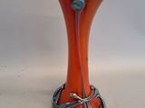 an orange glass vase with a blue bead on it