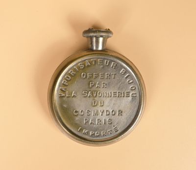 une montre de poche en argent posée sur une surface beige