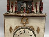 une petite horloge surmontée de figurines