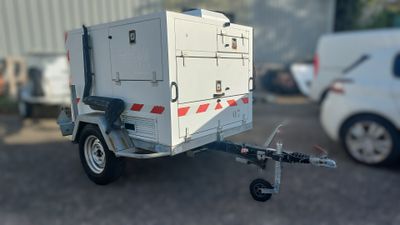 une petite caravane blanche à laquelle est attelée une remorque