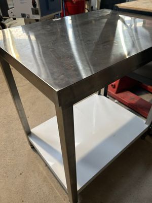 une table en métal surmontée d'une étagère, dans un entrepôt