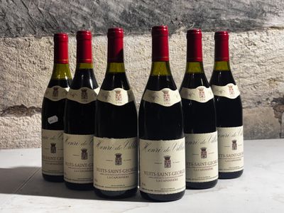 six bottles of wine are lined up on a table in front of a stone wall
