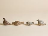 trois petits oiseaux en céramique assis les uns à côté des autres sur une surface blanche
