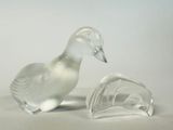 deux canards en verre transparent posés l'un à côté de l'autre sur une surface blanche