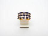 un gros plan d'une bague ornée de pierres bleues sur un fond blanc