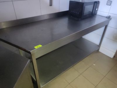 un micro-ondes posé sur un plan de travail en inox dans une cuisine