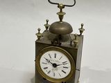 a small metal clock with a bell on top of it