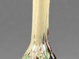 a glass vase with a white handle on a gray surface