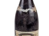 une vieille bouteille de vin posée sur une surface blanche