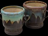 two cups that are sitting side by side on a black background