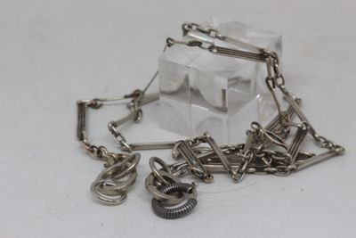 a silver chain with charms attached to it on a white surface
